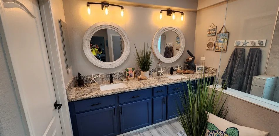 Remodeled bathroom with a navy double vanity and round mirrors in Rancho Cordova, CA
