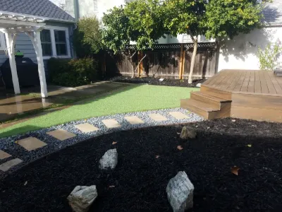 Turf, stepping stones and a wood deck in a backyard