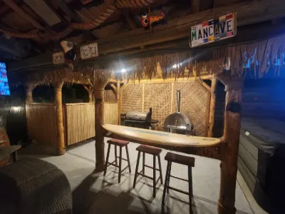 Tiki bar with a surfboard bar top, stools and a pizza oven