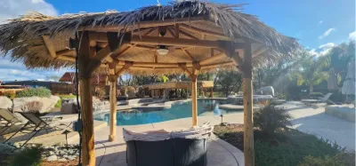 Palapa with lounge seating overlooking a backyard pool