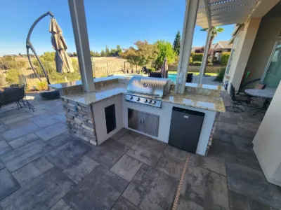 Stone-veneer outdoor kitchen with grill on a paver patio