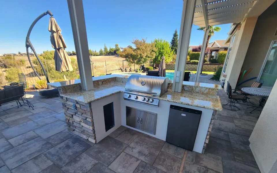 Stacked-stone outdoor kitchen with a built-in grill on a paver patio in Fair Oaks, CA