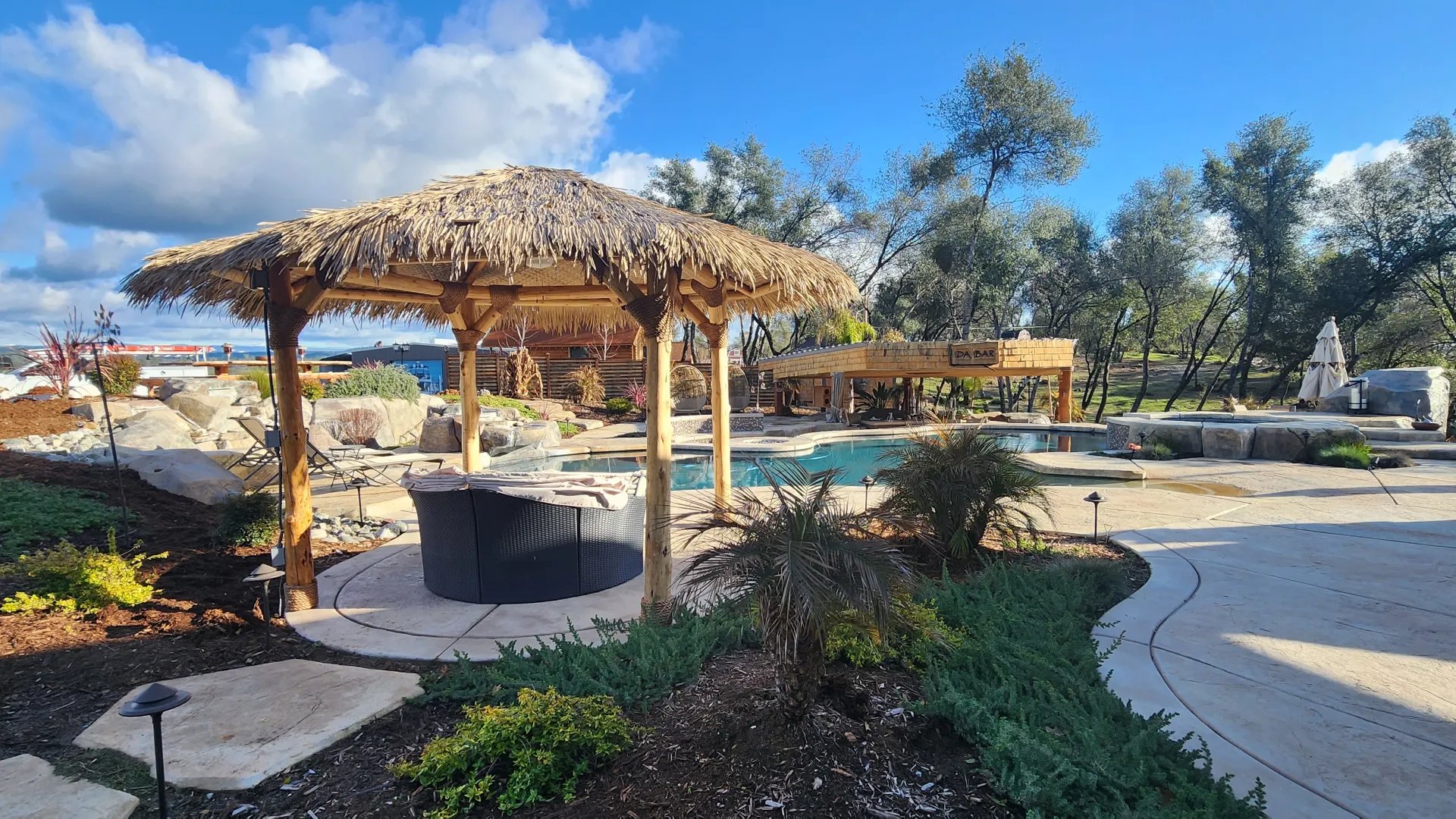 Thatched palapa behind a backyard pool