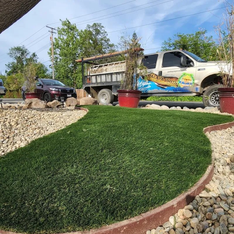 The branded Palapa Pros work truck parked beside a new synthetic-turf front yard